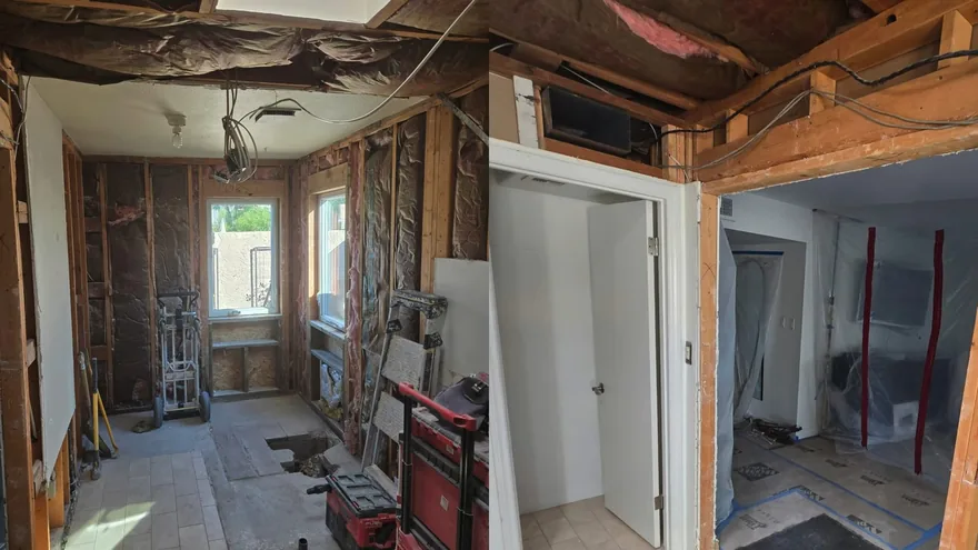 A gutted room with stripped wall framing and insulation, plastic sheeting in a doorway and a red tool case on the floor